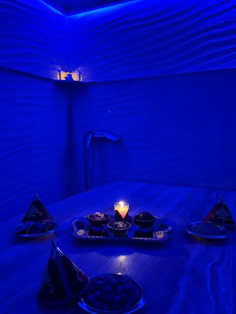 Hammam Prestina Spa baigné de lumière bleue, plateau de soins et bougie sur la table de marbre